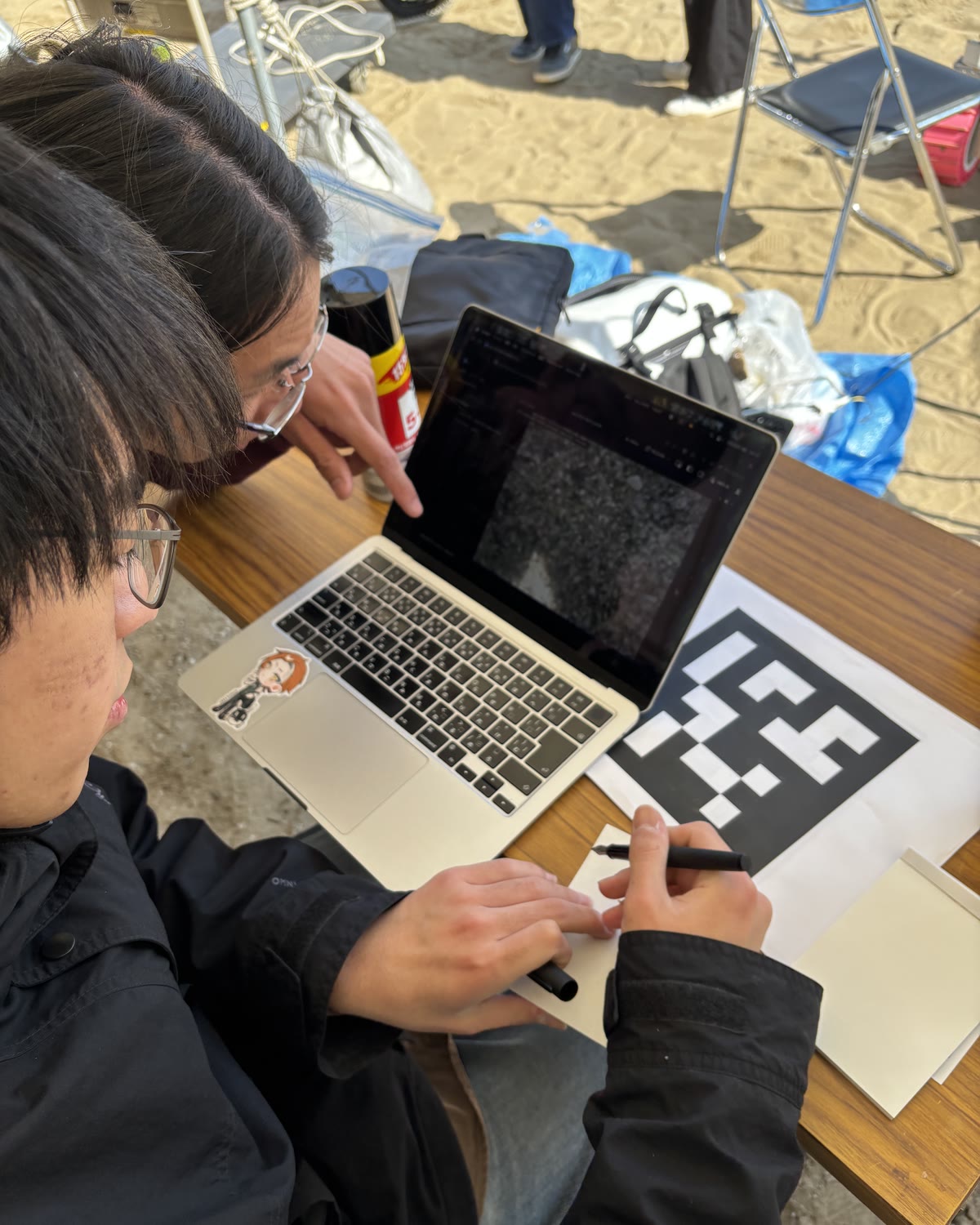 マーカーの紙を前に、パソコンで取得した画像を分析するメンバー