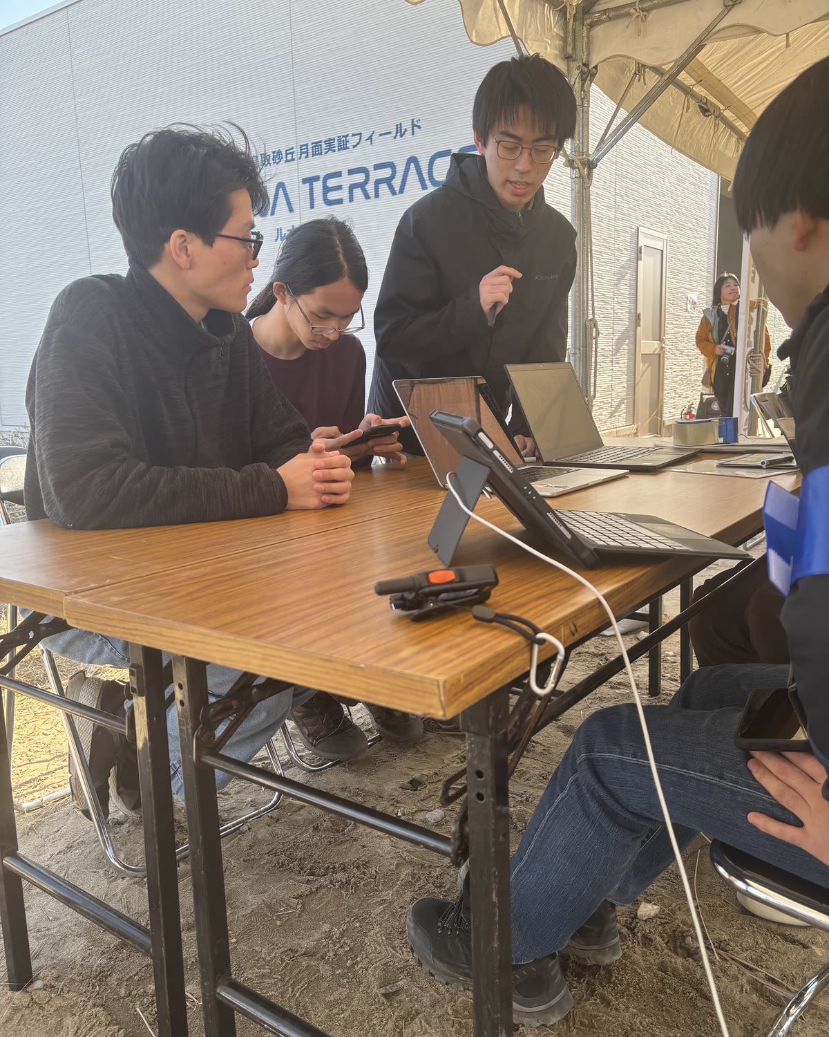 大会会場のテントで、分析の結果を報告するメンバー